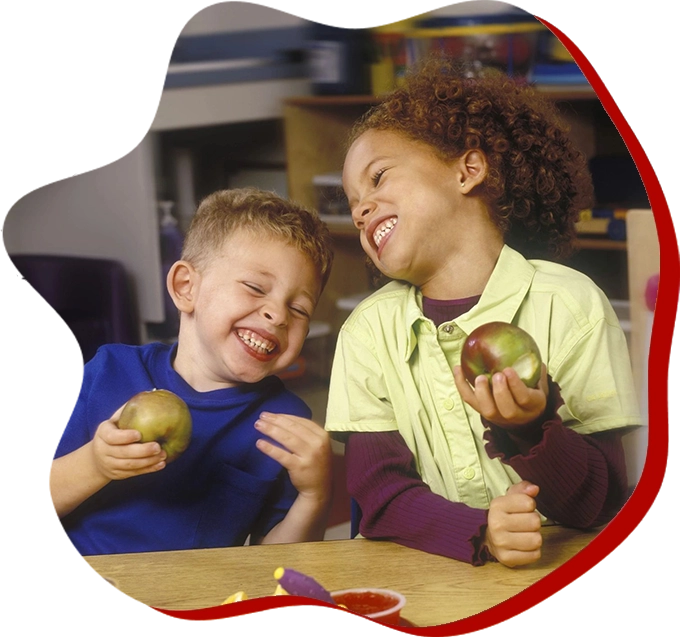 Two children are eating apples at a table.